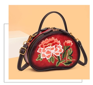 Detail view of red oval bag showing exquisite floral embroidery and leather texture