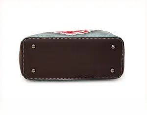 Detail of blue handbag bottom featuring metal rivets and floral embroidery texture