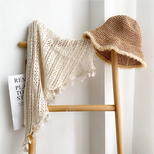 Châle en crochet beige à franges et chapeau de paille marron sur échelle