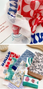 Detail of fabric texture and care label for the cotton-blend floral neck scarf