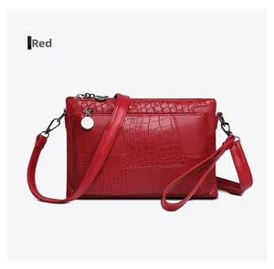 Close-up of red crocodile-patterned PU leather handbag with gold zipper and strap