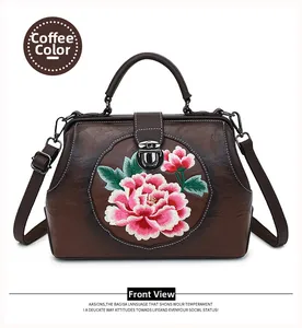 Close-up of pink peony flower embroidery and metal buckle on coffee leather handbag