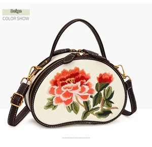 Close-up of beige leather crossbody bag with peony floral embroidery and brown trim