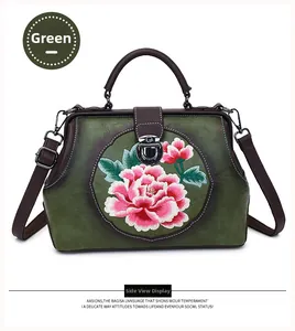 Detail of green leather handbag with pink peony embroidery and brown leather handles