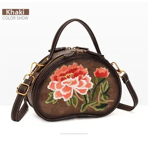 Close-up of khaki retro bean-shaped leather handbag with floral peony embroidery details