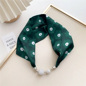 Detail of silk scarf featuring dark green floral prints and sparkling rhinestone magnetic clasps