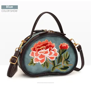 Detail of blue pod-shaped bag featuring vibrant floral embroidery and gold hardware