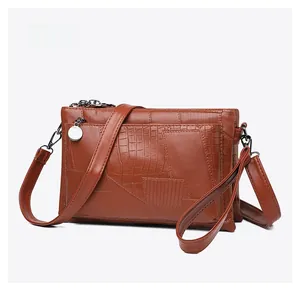 Detail of brown PU leather bag featuring elegant crocodile and grid textures with silver tag