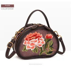 Detail of purple bean-shaped handbag with exquisite floral embroidery and golden hardware