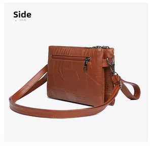 Detail view of the brown crocodile pattern texture and back zipper pocket of the PU bag