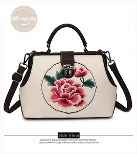 Close-up of pink peony embroidery on cream leather handbag with vintage metal clasp