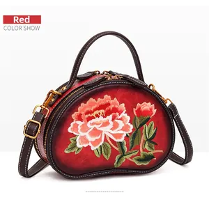 Detail of red floral embroidery on leather crossbody bag with dual zipper closure