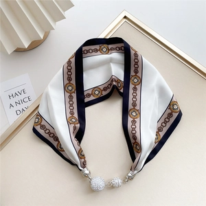 Detail of elegant cream silk scarf with vintage clock print and magnetic crystal buckle