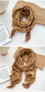 Detailed texture of tie-dye cotton linen scarf on wooden display with pleated lamp