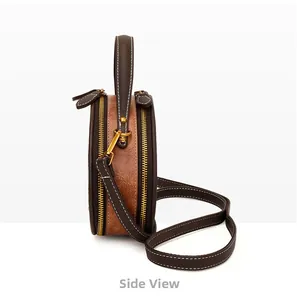 Side view of round crossbody bag in brown leather with white stitching and gold hardware