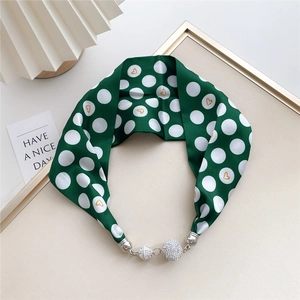 Macro detail of dark green polka dot silk scarf with sparkling rhinestone magnetic clasps