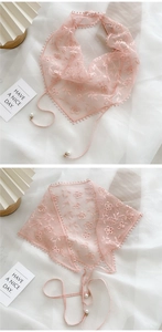 Détail d'un foulard en dentelle rose avec broderie florale et accents de perles