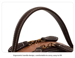 Detail view of smooth rounded handle and vintage gold zipper on printed crossbody bag