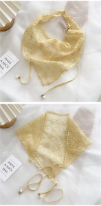 Détail d'un foulard triangle en dentelle beige avec broderie florale et perles