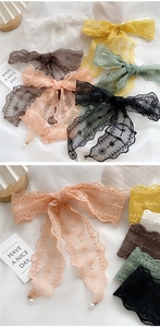 Close-up of lace hair ribbons with floral embroidery and pearl pendant charms