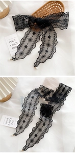 Detail of black lace ribbon with floral embroidery and white pearl pendants on edges