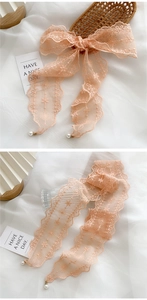Detail of light pink floral lace ribbon with white pearl pendant and scalloped edges