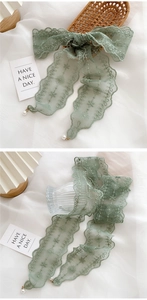 Detail of light green lace ribbon with floral embroidery and pearl pendants