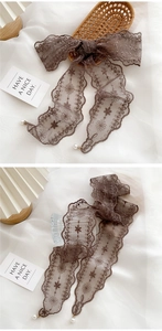 Detailed embroidery on a dark brown lace scarf with elegant white pearl pendant charms