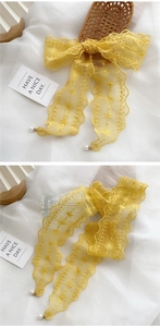 Detail of yellow lace scarf with floral embroidery and white pearl pendants