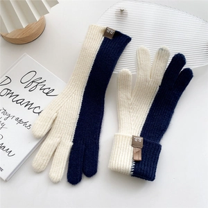 Detail of blue and white split-finger knit gloves with leather tag and ribbed texture