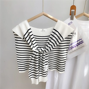 Détail d'un châle en tricot à rayures noires et blanches avec nœud et texture douce