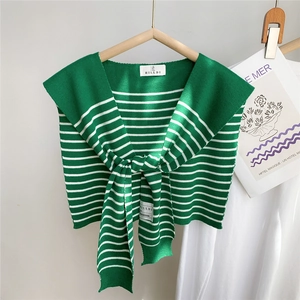 Détail d'un châle en tricot à rayures vertes et blanches avec un nœud et une étiquette