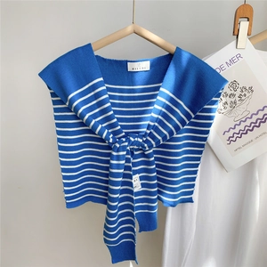 Détail d'un châle en maille à rayures bleues et blanches avec étiquette de marque et noué