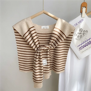 Détail du châle en maille rayée montrant la texture beige et marron et l'étiquette