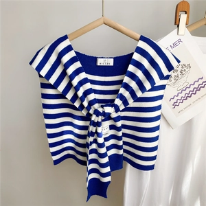 Détail d'un châle en tricot à rayures bleues et blanches avec nœud décoratif sur un cintre