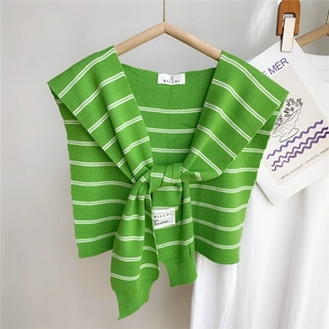 Détail d'un châle en tricot à rayures vertes avec nœud et étiquette de marque