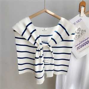 Détail du châle en tricot à rayures bleu marine avec étiquette de marque sur un cintre