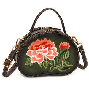 Green leather crossbody bag with peony embroidery and brown trim on white background
