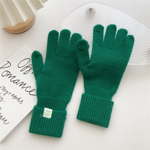 Detail of dark green knitted gloves with folded ribbed cuffs and high-quality material texture