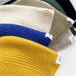Colorful knitted beanie hats with rib texture and decorative labels in various trendy colors