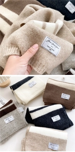 Close-up of thick striped knit scarves showing soft texture and woven brand labels