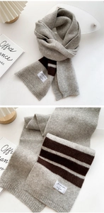 Detail of soft gray knitted scarf with brown stripes and vintage brand woven label