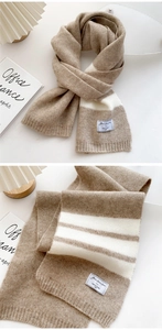 Close-up of soft knitted scarf featuring beige stripes and woven brand label detail