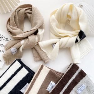 Long striped knit scarf in soft thick material featuring neutral colors and woven labels