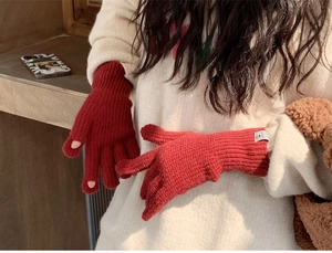 Detail of red knit gloves with finger openings for touchscreen use and ribbed cuffs