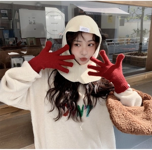 Close-up of beige knitted hood scarf and red gloves set for winter outdoor warmth