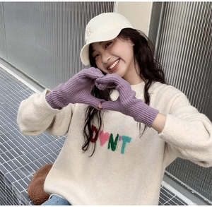 Close-up of purple knitted fingerless gloves worn by a model in a cozy winter street setting