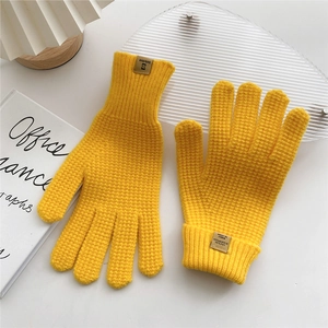Detail of yellow knit gloves showing waffle texture and fabric composition label
