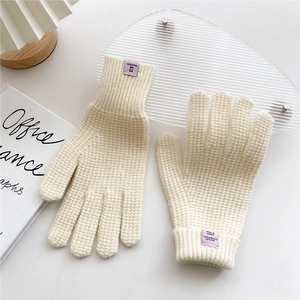 Detail of cream knit gloves showing 70% acrylic material tag and soft texture