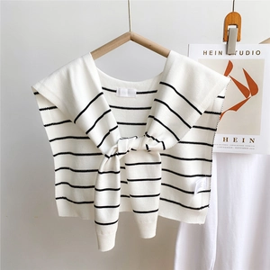 Detail of black and white striped knit shawl accessory with neck ties on wooden hanger